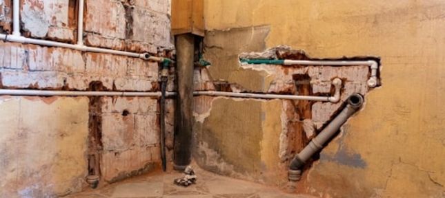 An interior view of a bathroom with exposed pipes